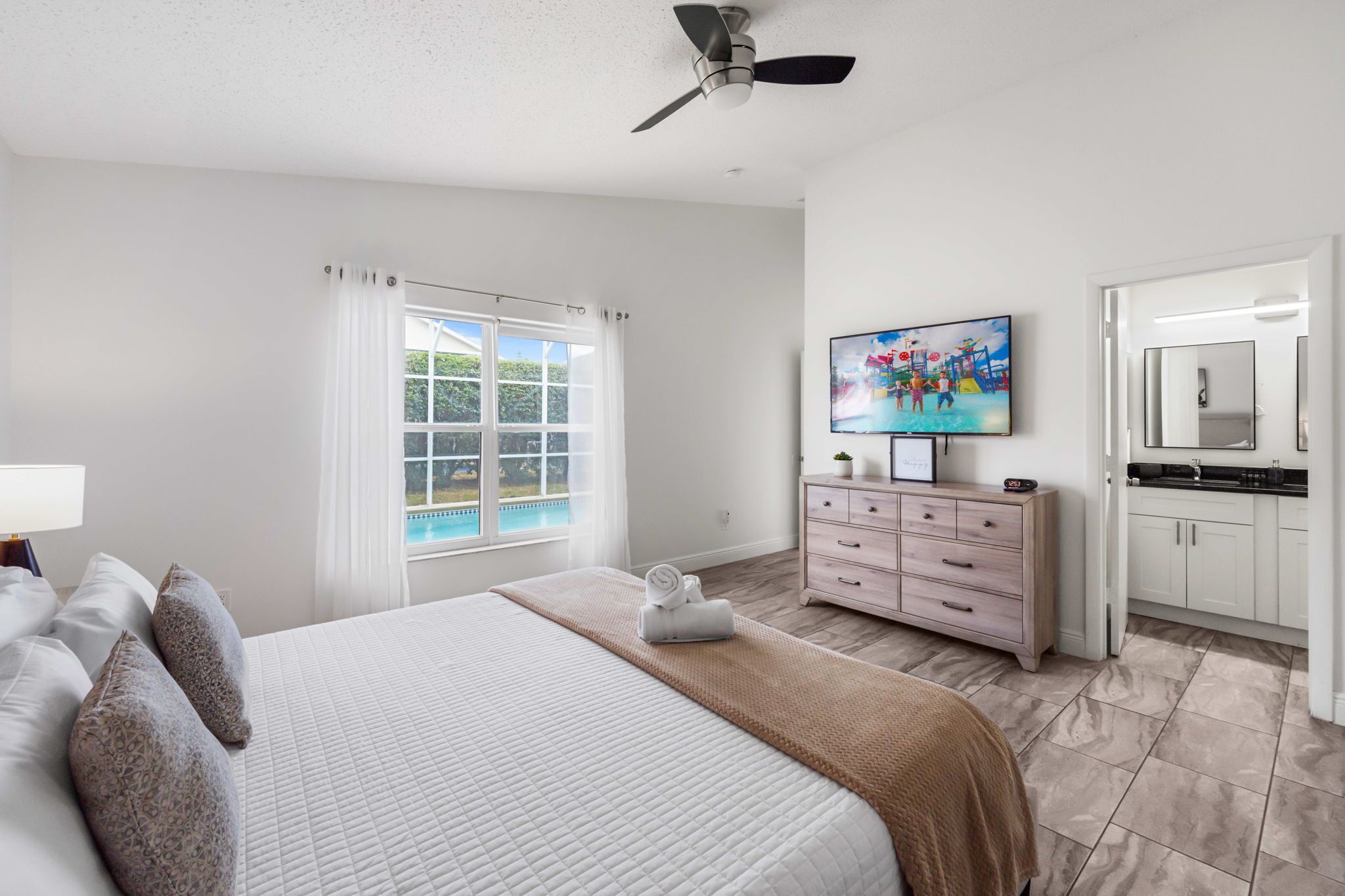 Quarto de hotel com cama, televisão, banheiro e vista para a piscina.