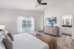 A hotel room with a bed, a TV, a bathroom, and a view of a pool. - NEW LISTING Amazing Location! 4BR, Pool, Mid-Term Stays! Close to Disney! (Davenport)