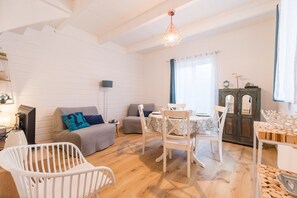 Una sala de estar acogedora con un sofá blanco, una mesa de comedor con sillas, una cuna para bebé y un mueble de madera.