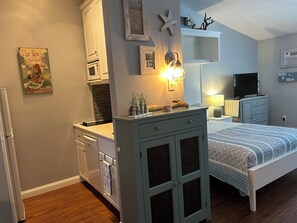 Une chambre à coucher comprenant un lit, une commode, une coiffeuse et un téléviseur.