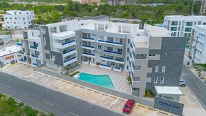 Un hotel moderno de varios pisos, con piscina, varios balcones y un área de estacionamiento.