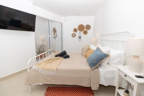 A bedroom with a bed, bedside table, lamp, and wall decor. - Caribbean Getaway 2BR at Caribbean Rose Bayahibe (San Rafael del Yuma)
