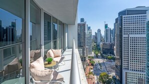Ein Balkon mit Blick auf die Stadt, eine Couch und ein kleiner Tisch mit einer Pflanze.