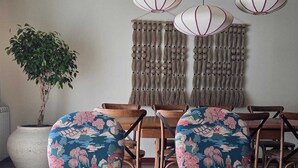 A dining area with wooden chairs and a table, a hanging light fixture, and a large potted plant. - Villa do Canal (Apúlia)