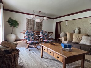 A living room with a wooden coffee table, floral armchairs, a sofa, and a dining area with a table and chairs. - Villa do Canal (Apúlia)
