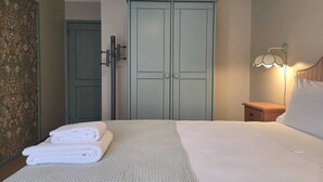 A hotel room with a bed, a nightstand, a lamp, a wardrobe, and a door. - Villa do Canal (Apúlia)