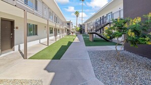 Een modern gebouw met een centrale pad, palmbomen en een kleine tuin.