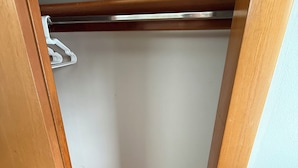 Un petit placard fermé, doté d’une porte en bois et d’une tringle métallique pour suspendre les vêtements.