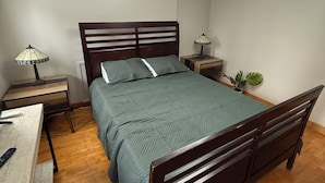 Une chambre à coucher comprenant un lit, des tables de chevet, un bureau et un luminaire au plafond.