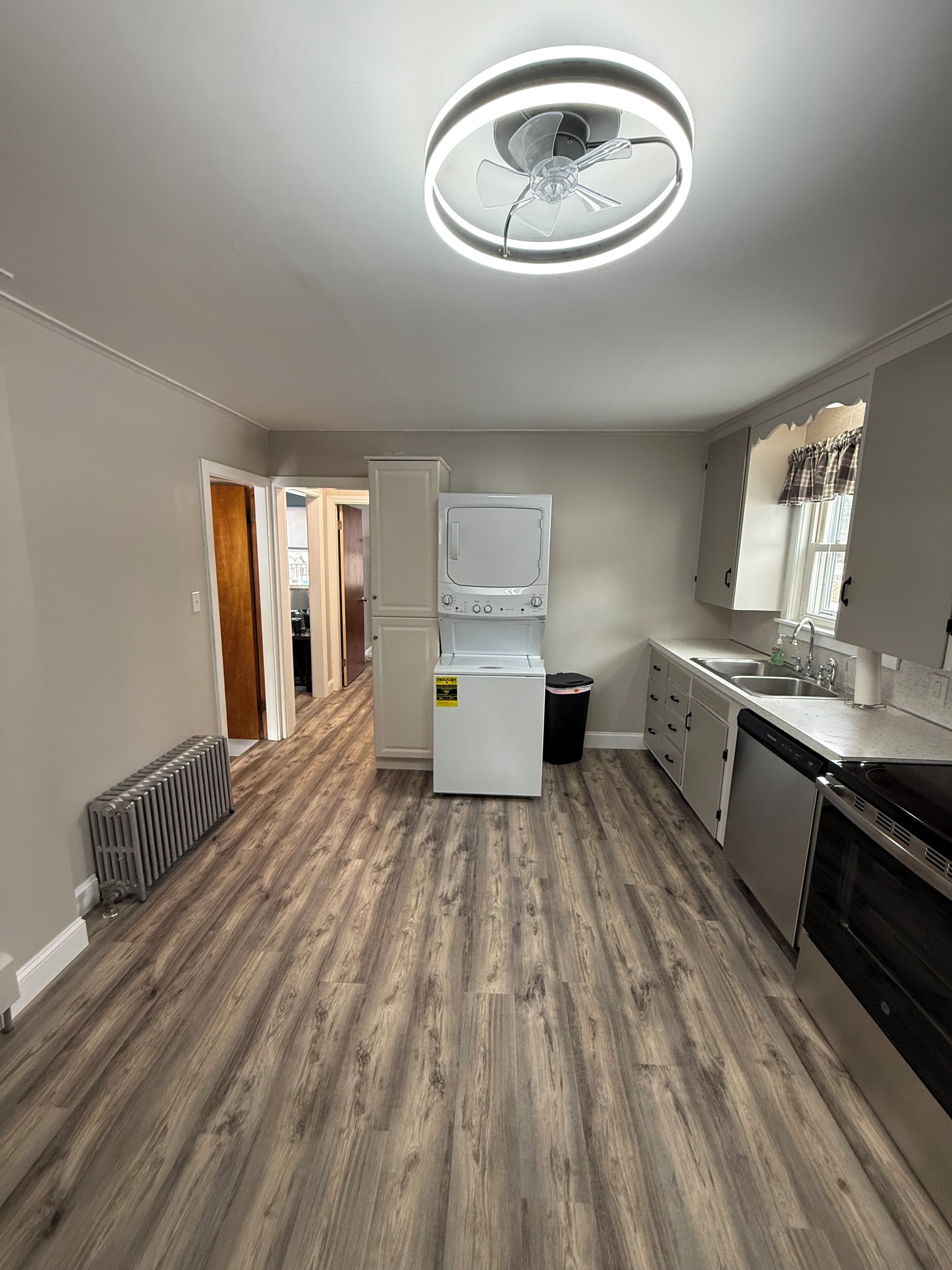 A modern kitchen with a built-in oven, a dishwasher, and a large window.