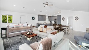 Ein modernes Wohnzimmer mit Sofa, Couchtisch und einem Essbereich mit Tisch und Stühlen.