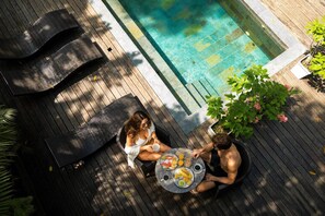 A poolside area with a wooden deck, lounge chairs, and a table with food and drinks. - RINCON DE LA SIERRA MINCA (Minca)