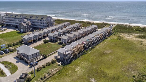 Un hôtel situé sur la côte, composé de plusieurs bâtiments, dont un grand hôtel et plusieurs unités plus petites, tous offrant une vue directe sur l’océan.