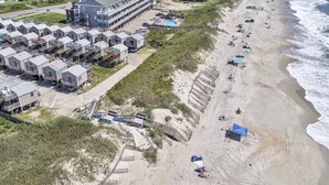 Vue aérienne d’un hôtel situé sur la côte, composé de plusieurs bâtiments, avec une plage et une promenade en bord de mer.
