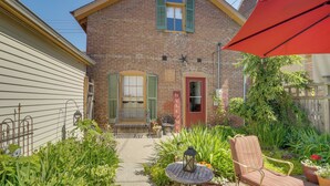 A brick house with a red door, a bench, and a garden with various plants.