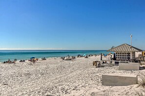 Una spiaggia con un edificio, un'antenna, una tenda e persone che si rilassano.