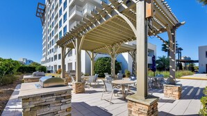 Un'area patio con posti a sedere esterni, un camino in pietra e una pergola.