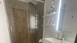 Un bagno moderno con doccia vetrata, un water bianco e un mobile lavabo con specchio.