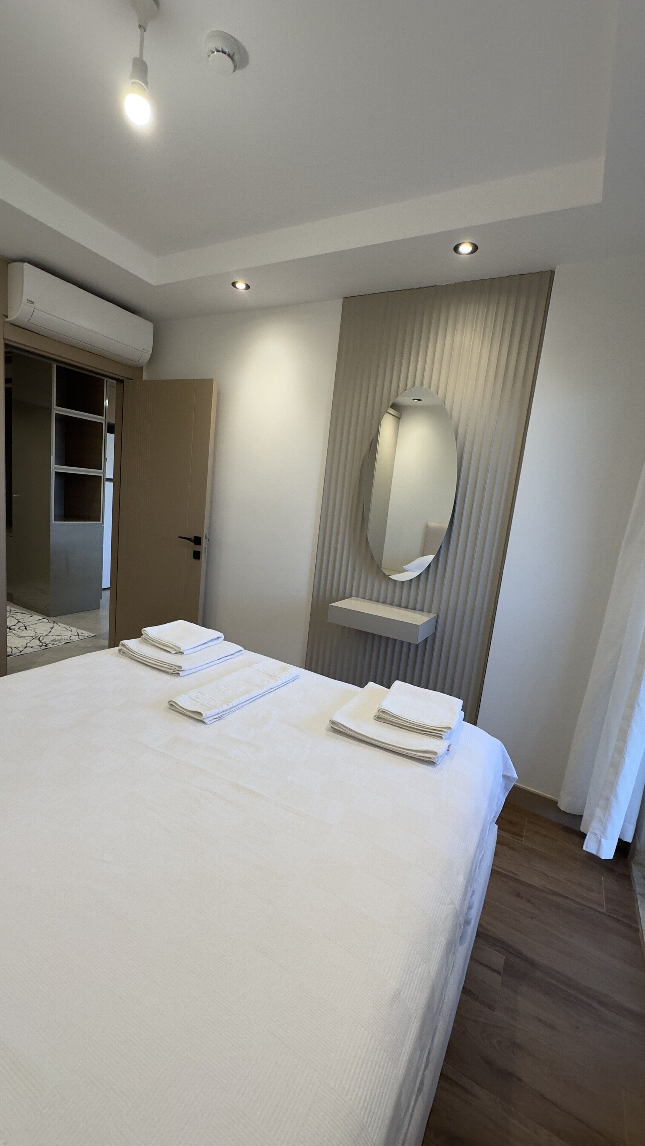 Ein Hotelzimmer mit einem großen Bett, einem Spiegel und einer fest installierten Klimaanlage.