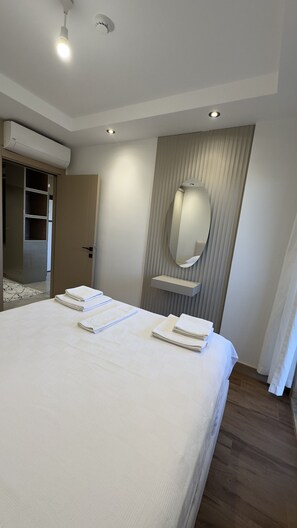 Une chambre d’hôtel avec un grand lit, un miroir et un système de climatisation intégré.