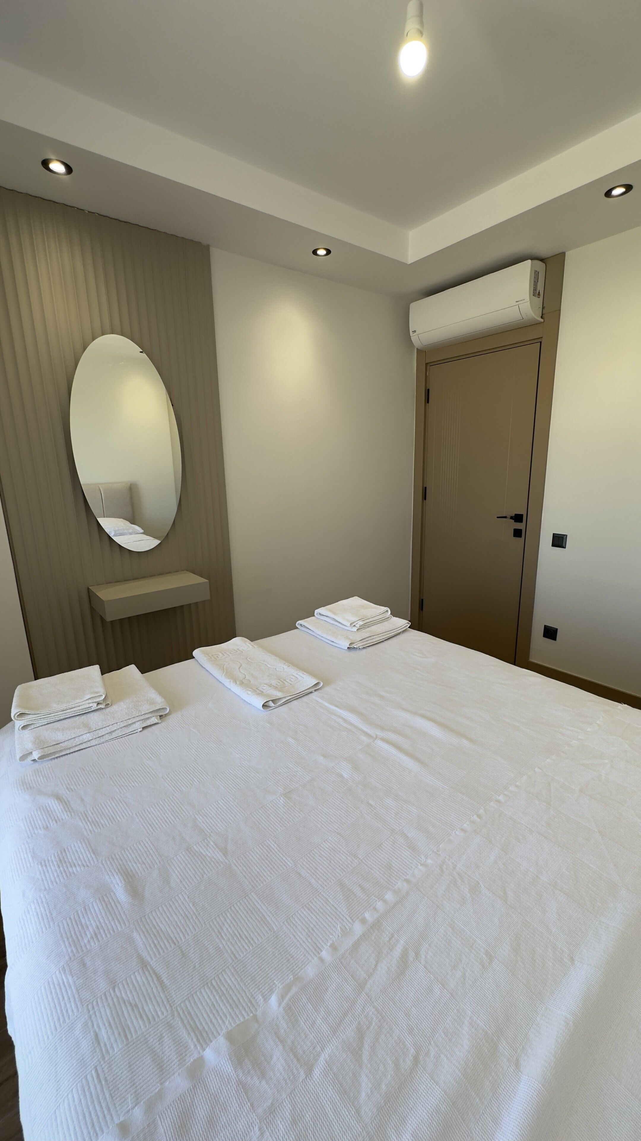 Ein Hotelzimmer mit einem großen Bett, einem Spiegel, einem Nachttisch und einer Klimaanlage.