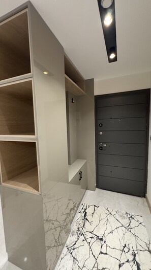 Ein Zimmer mit einer dunklen Tür, einem weißen Marmorboden und eingebauten Regale.