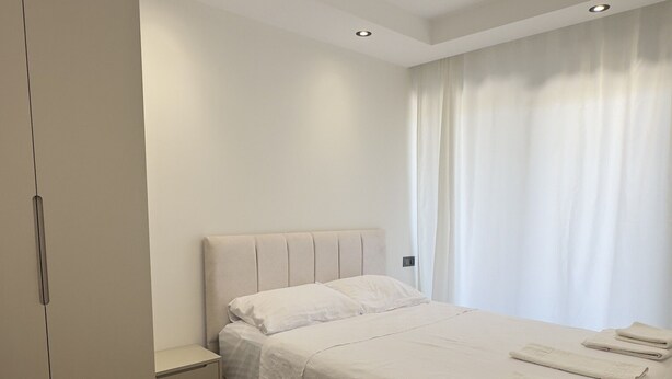 A bedroom with a bed, a wardrobe, and a window with curtains. - NestParkSide (Manavgat)