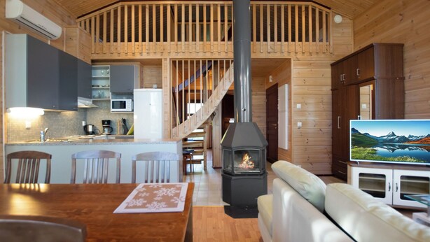 Een houten blokhut van binnen met een keuken, eethoek en woonkamer.