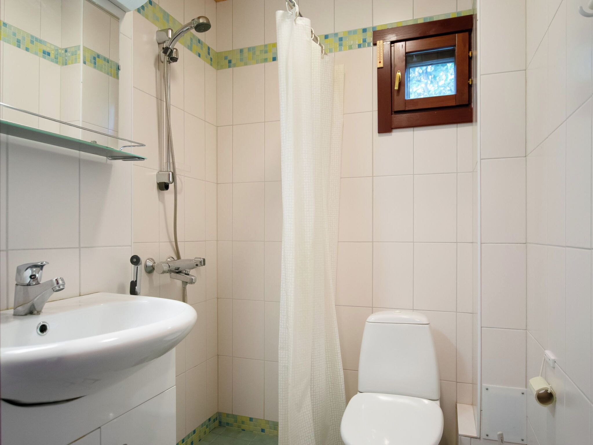 Kylpyhuone, jossa on valkoinen pesuallas, lasiovilla varustettu suihku ja wc.