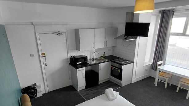 A hotel room with a bed, a kitchenette, a TV, and a window with curtains. - Standard Triple Ensuite (Skegness)