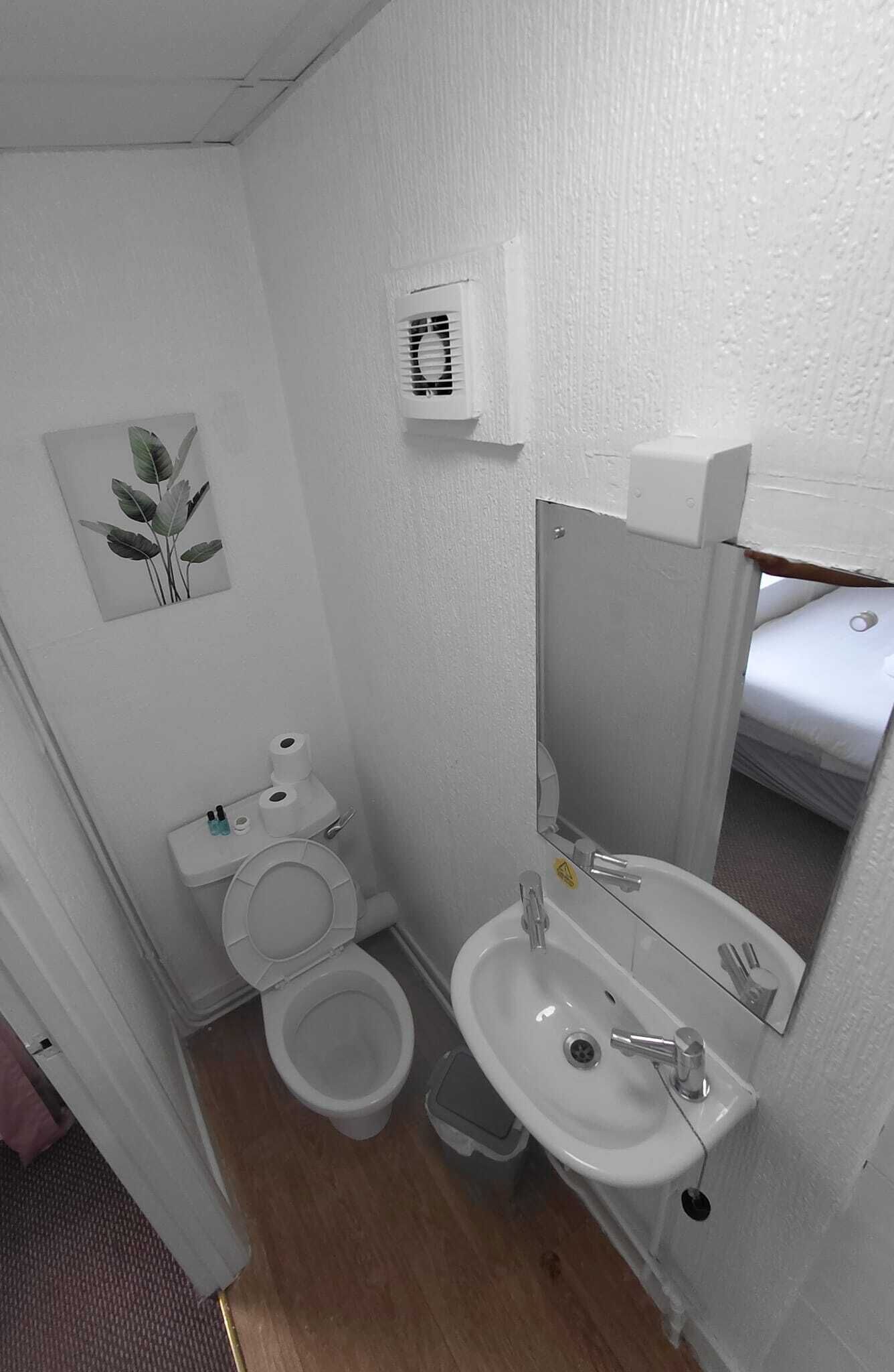 A small, compact bathroom with a toilet, sink, and mirror.
