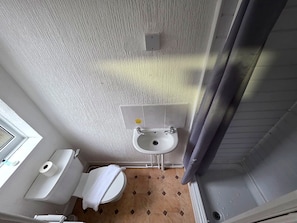 Ein kleines Badezimmer mit Toilette, Waschbecken und Duschbereich.