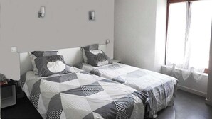 Un dormitorio con dos camas, una ventana con cortinas y dos lámparas de pared.