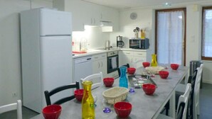 Una cocina con armarios blancos, un refrigerador, un microondas y una mesa de comedor con platos rojos y amarillos.