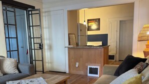 A living room with a sofa, a coffee table, and a kitchen area in the background. - Charming Historic Downtown Apartment, One Bedroom, with Enclosed Patio (Tucson)