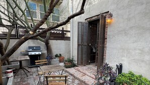 An outdoor patio with a brick floor, a wooden table, and a bench. - Charming Historic Downtown Apartment, One Bedroom, with Enclosed Patio (Tucson)
