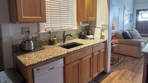 A compact kitchen with wooden cabinets, a built-in dishwasher, and a granite countertop. - Charming Historic Downtown Apartment, One Bedroom, with Enclosed Patio (Tucson)