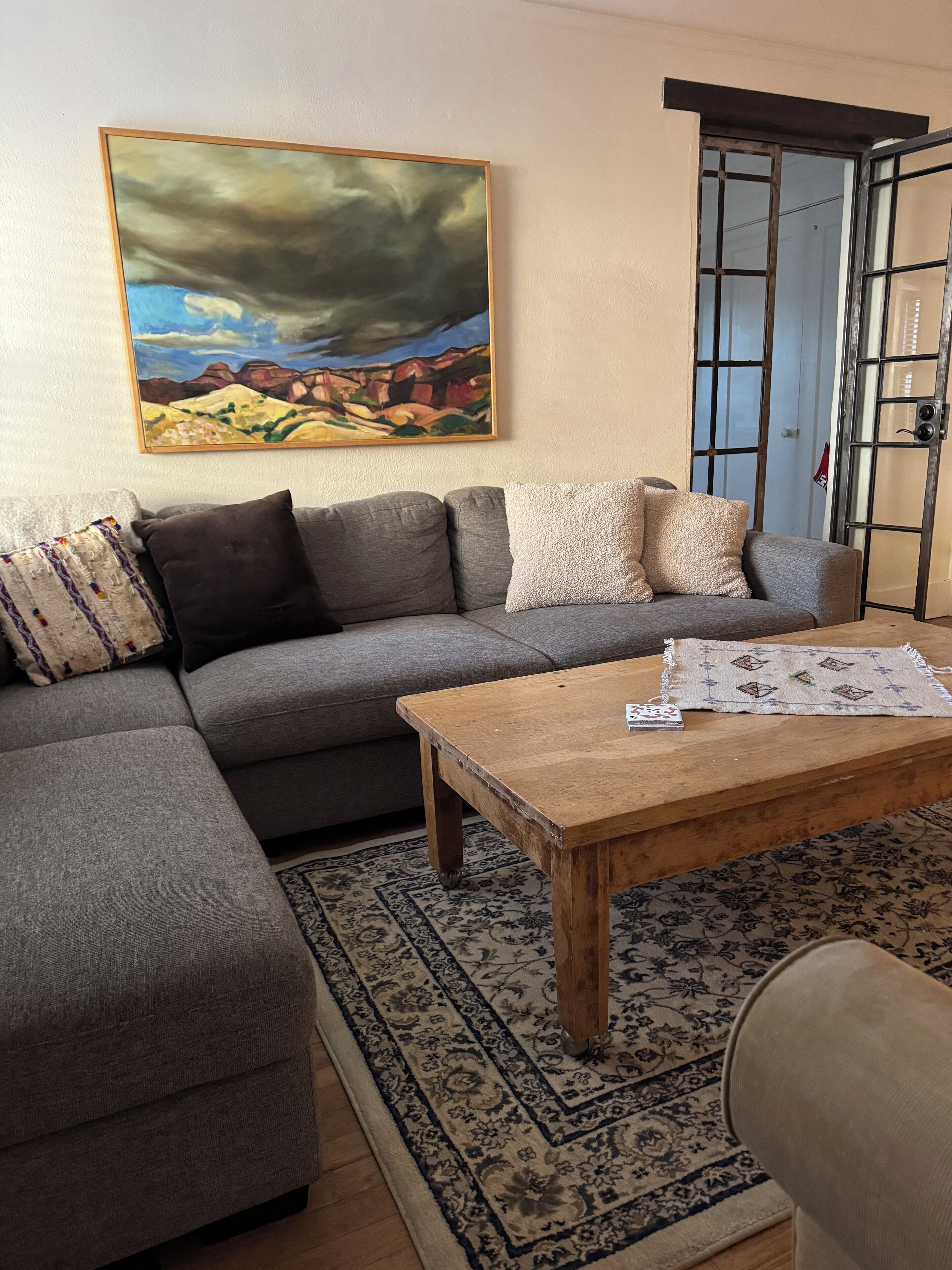 A living room with a grey sofa, a wooden coffee table, and a patterned rug.