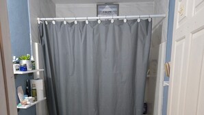 Pieni kylpyhuone, jossa on wc, pesuallas ja kylpyamme.