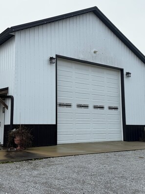 A white building with a large garage door and two small windows on the side. - Quiet Countryside Escape – Relax & Unwind (Hickory)
