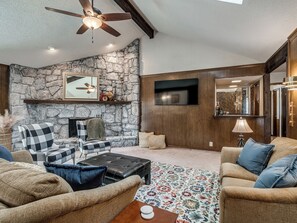 Ein Wohnzimmer mit Steinwänden, Kamin, Deckenventilator und Fernseher.