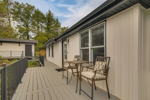 Eine überdachte Terrasse mit Tisch, Stühlen, einer Tür und einem Fenster.