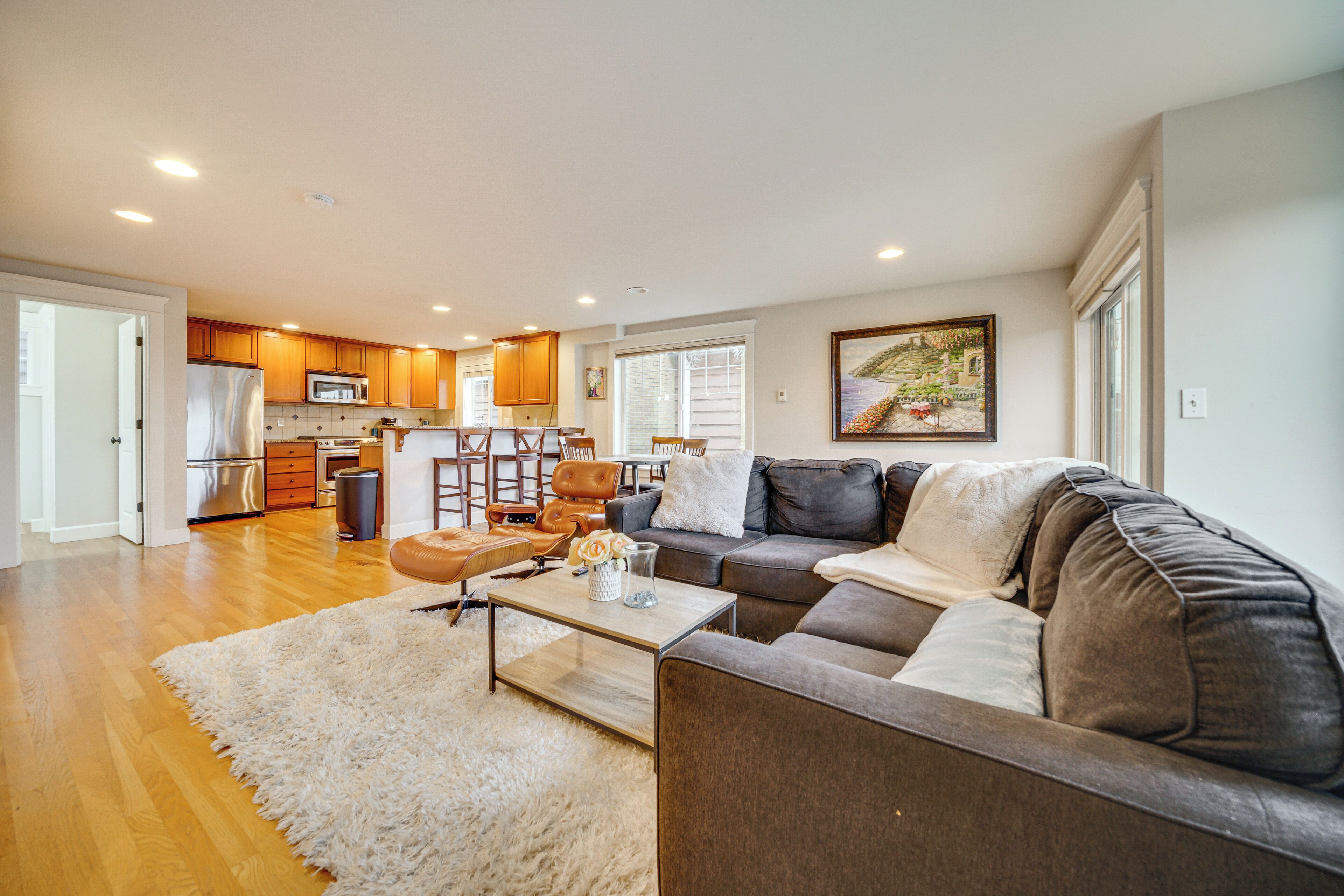 A modern living room with a sectional sofa, a coffee table, and a kitchen in the background.