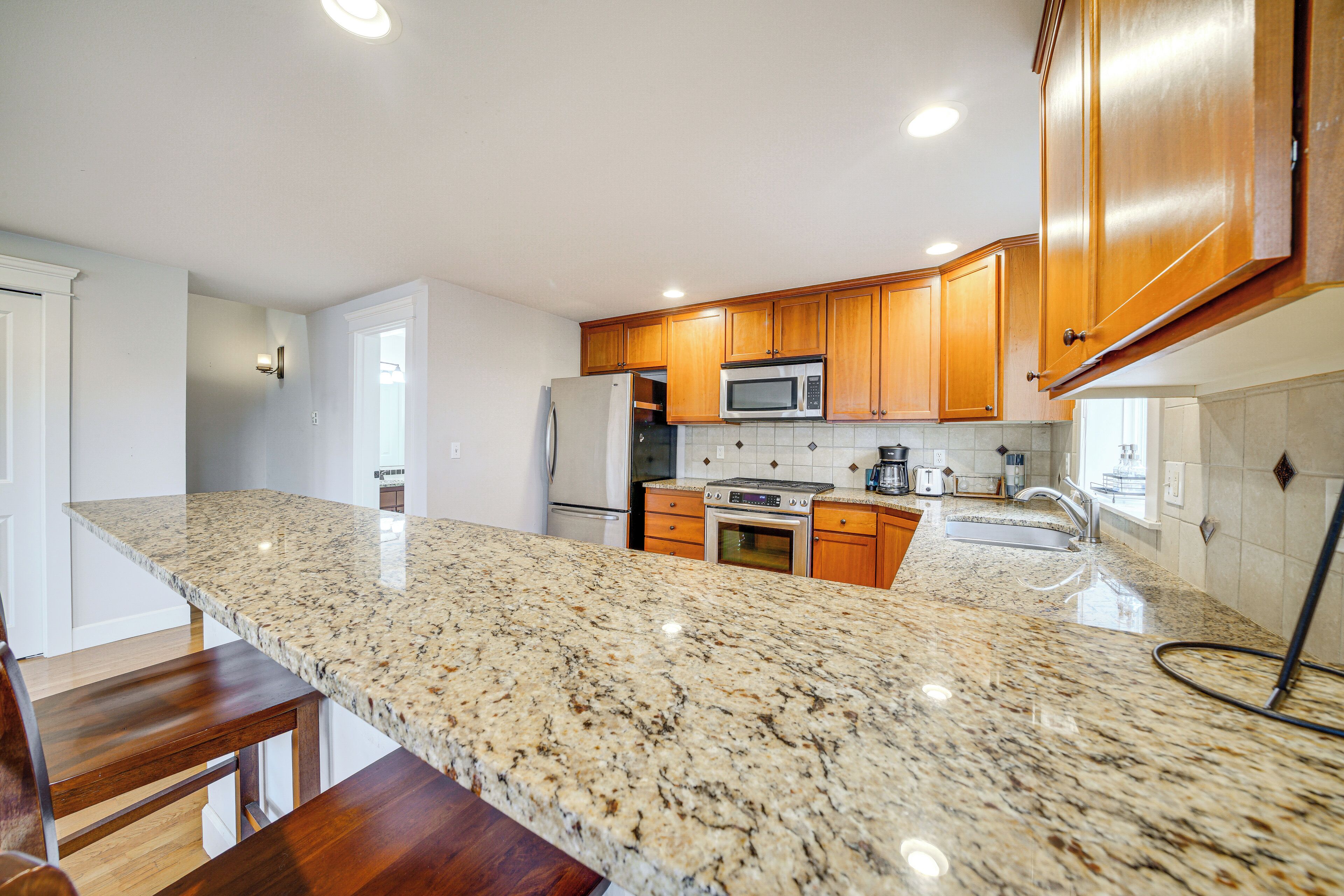 A kitchen with granite countertops, wooden cabinets, stainless steel appliances, and a built-in oven.