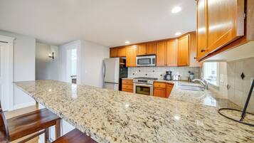 A kitchen with granite countertops, wooden cabinets, stainless steel appliances, and a built-in oven.