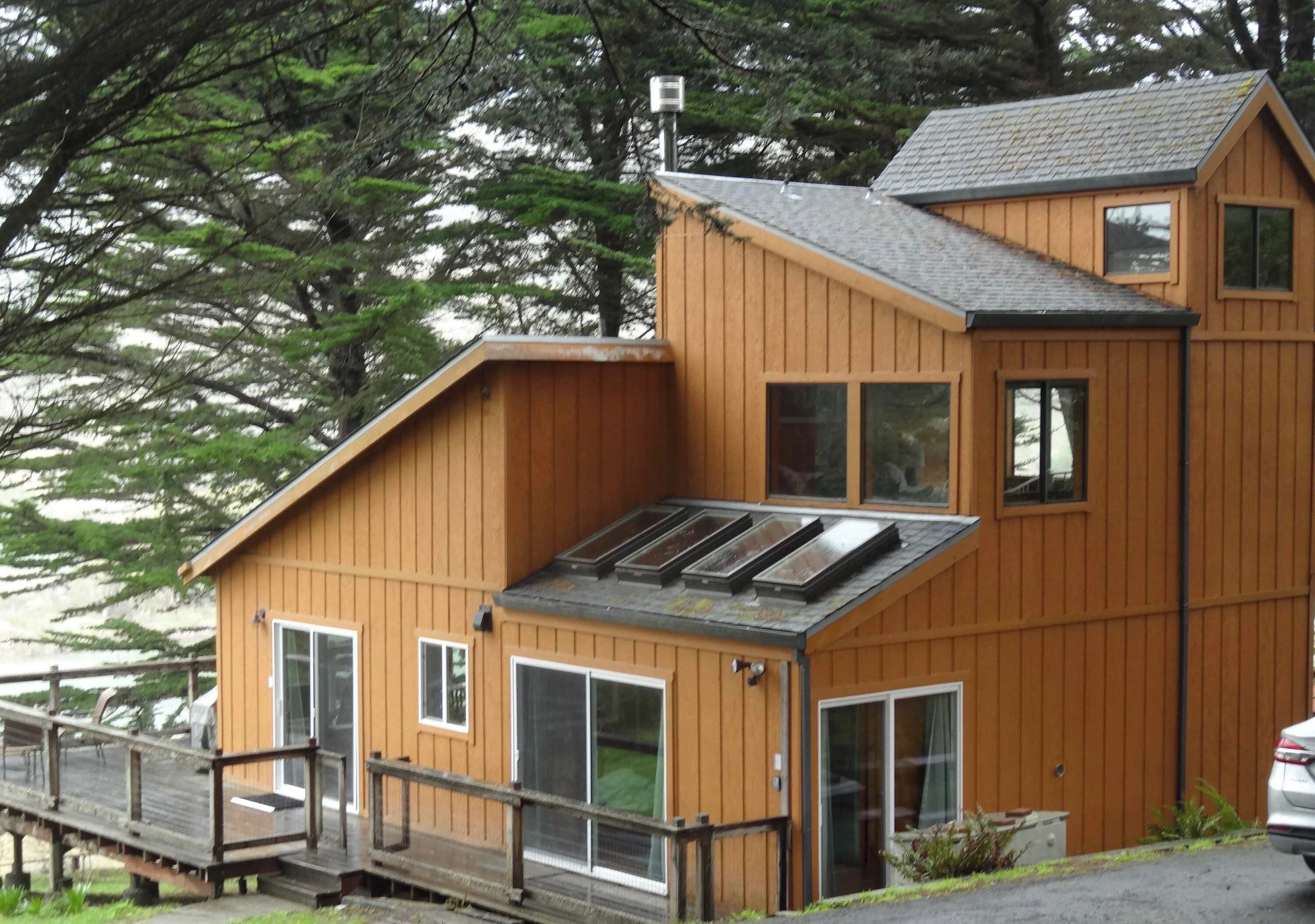 A wooden cabin with a sloped roof, large windows, and a deck.