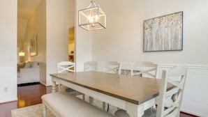 A dining area with a wooden table and white chairs, a bench, a chandelier, and a painting on the wall. - 11 Mi to Savannah! Suburban Home w/ Spacious Yard (Pooler)