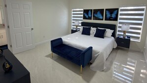 Een slaapkamer met een bed, een bankje, een plafondventilator en vlinderdecoratie aan de muur.