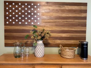 A wooden wall with a star pattern, a vase with dried flowers, a glass pitcher, a woven basket, and a black thermos. - Luxury Cabin Near Asheville Creekside Hot Tub 3 King Suites Blue Ridge Mountains (Bakersville)