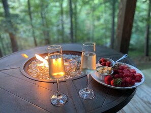 Un tavolo di legno rotondo con due bicchieri di vino bianco e un piatto di fragole e lamponi.